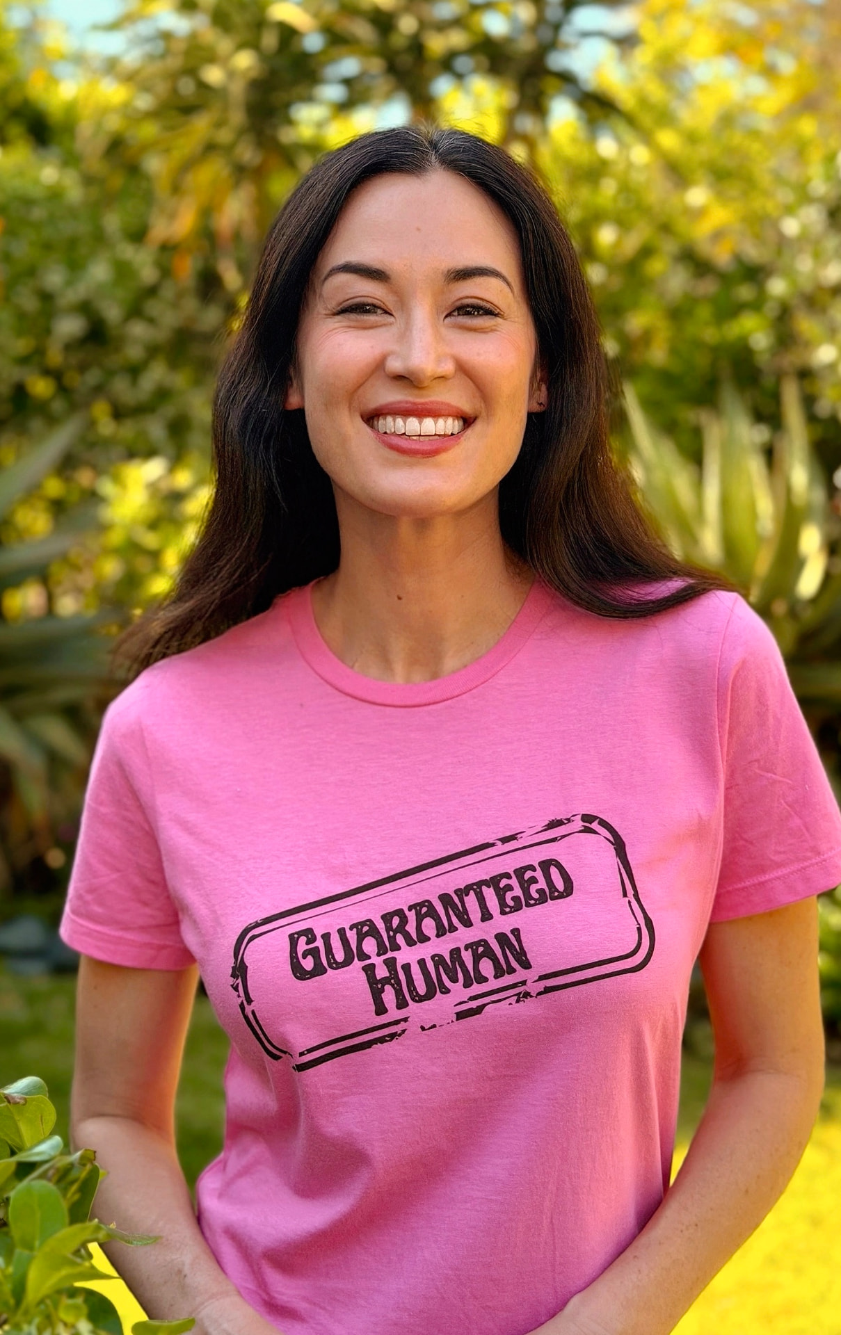Woman wearing the pink Guaranteed Human™ stamp tee